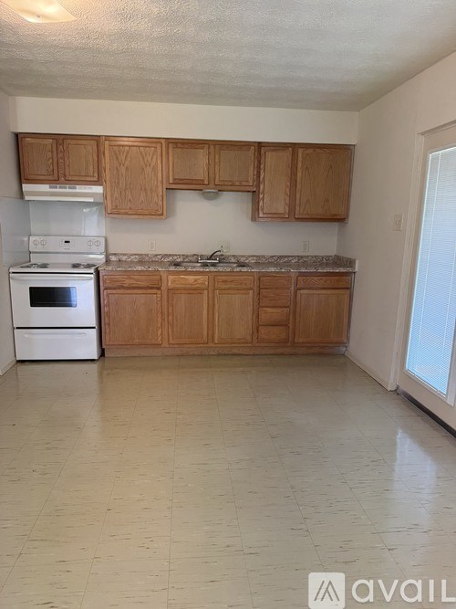 A kitchen with wooden cabinets and a white stove top oven.