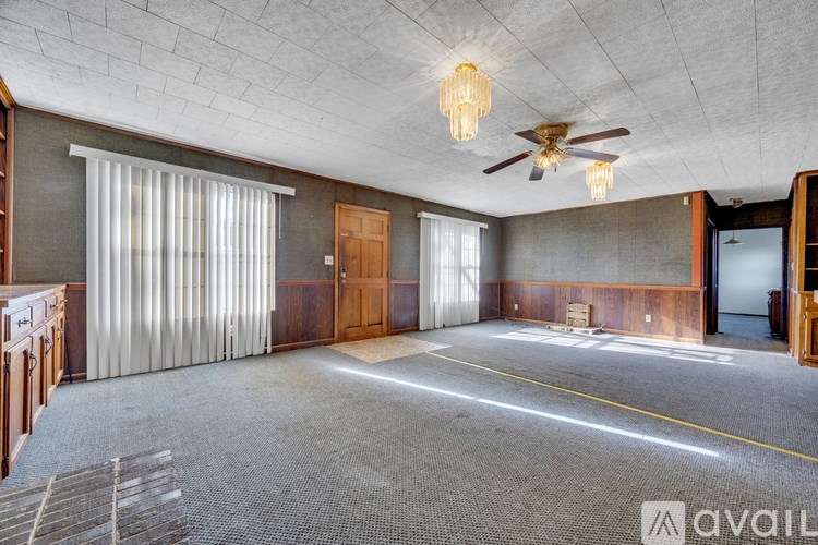 A spacious room with a ceiling fan and a large window with curtains.