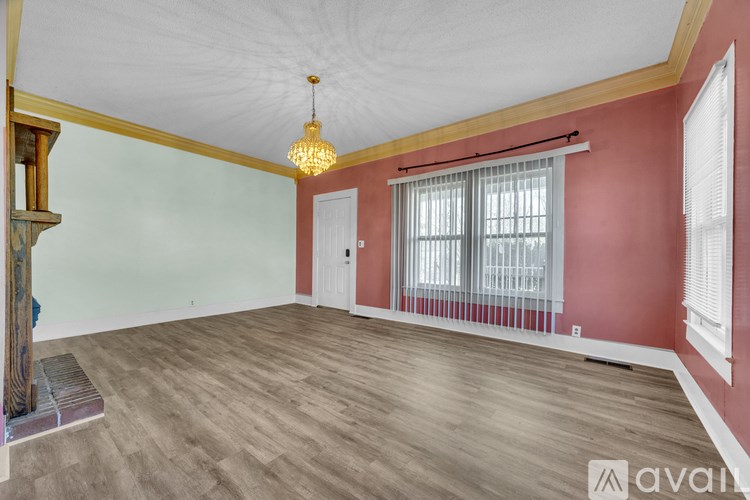 A room with wooden floors and a chandelier hanging from the ceiling.