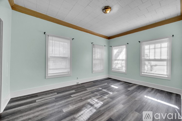 A room with light green walls, a wooden ceiling, and a grey wood floor.