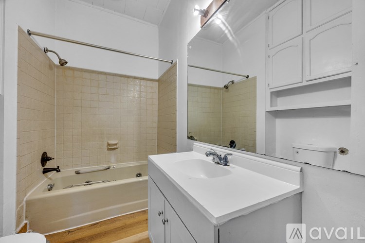 A white bathroom with a tub, sink, and mirror.