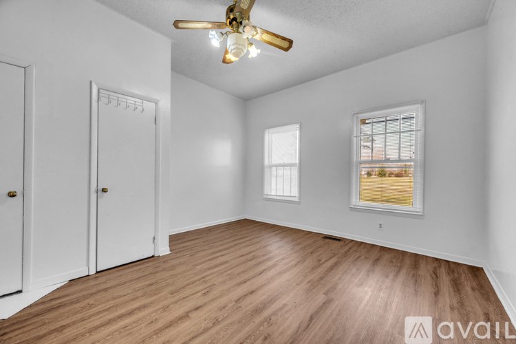 A room with a ceiling fan and wooden flooring.