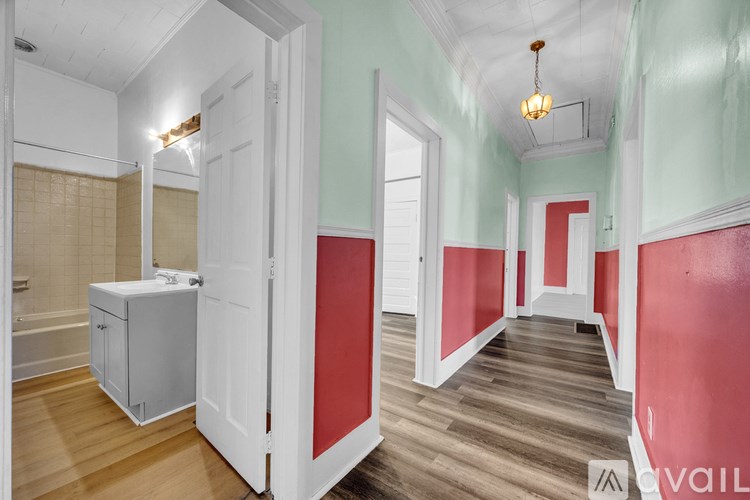 A bathroom with a white tub and sink, and a wooden floor.