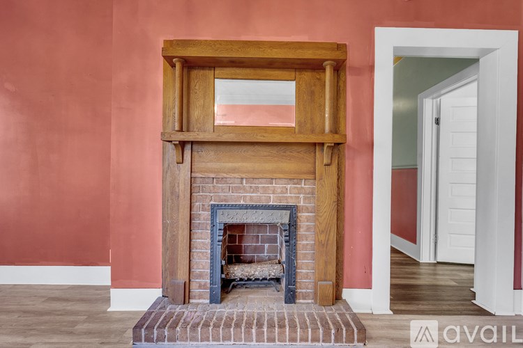A fireplace with a wooden frame and a brick base is in the corner of a room.