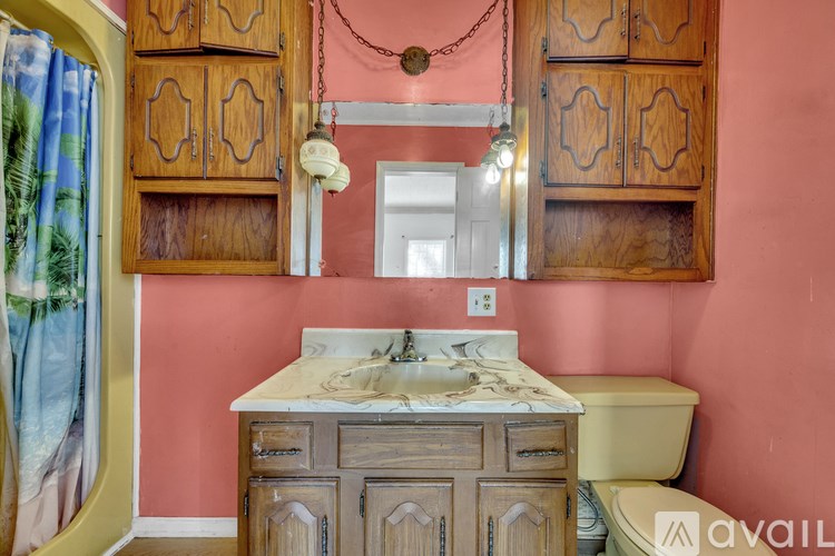 A bathroom with a sink, toilet, and wooden cabinets.