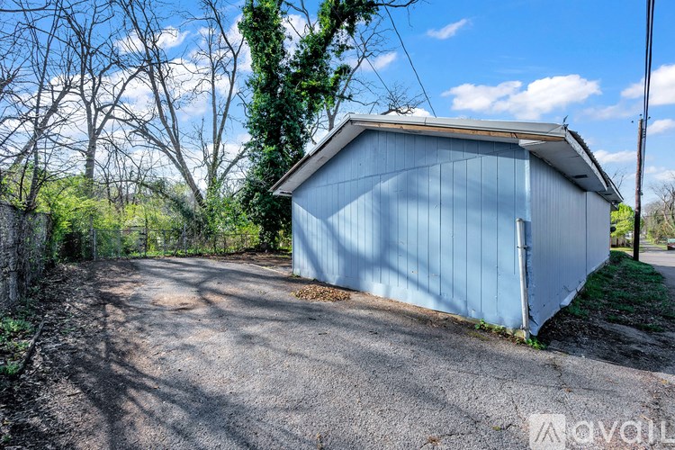 A blue shed sits on the side of a dirt road.