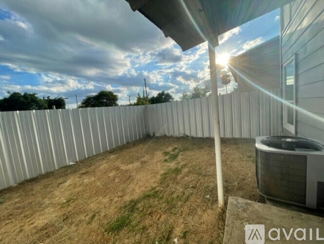 A backyard with a fence and a wall-mounted air conditioning unit.