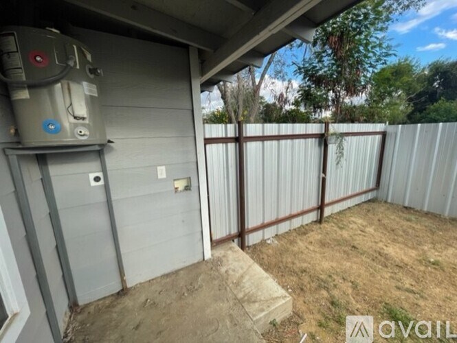A backyard with a fence and a utility box on the side of a house.