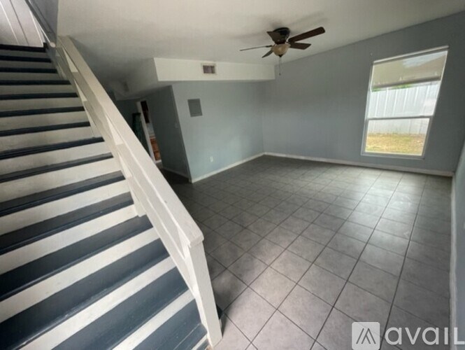 A room with a staircase and a ceiling fan.