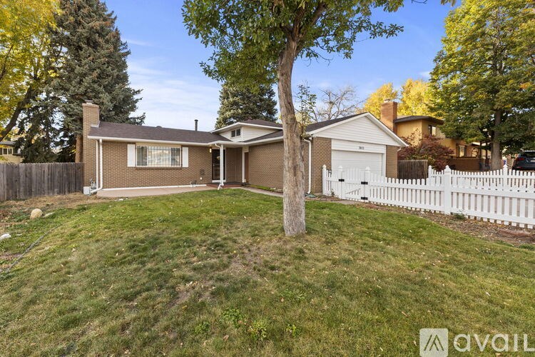 A house with a white fence and a tree in the front yard.
