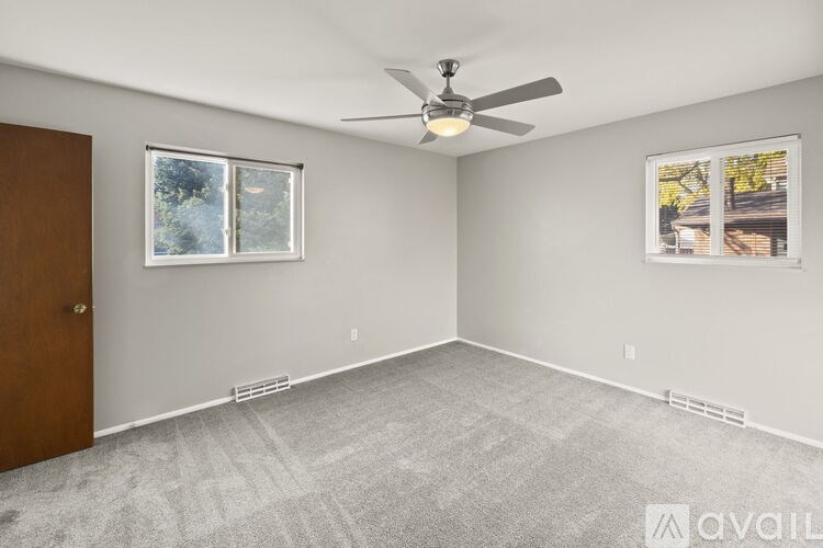 A room with a ceiling fan and two windows.