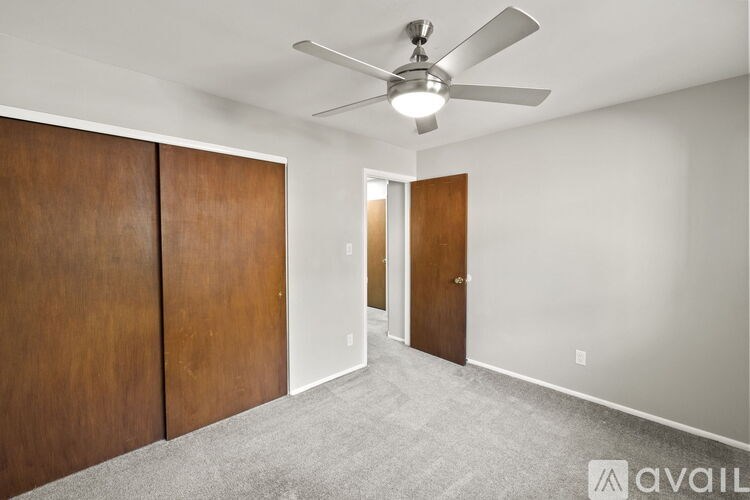 A room with a ceiling fan and a door.