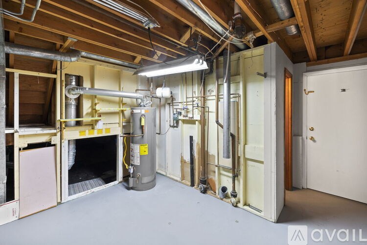 A room with a lot of pipes and a door on the right.