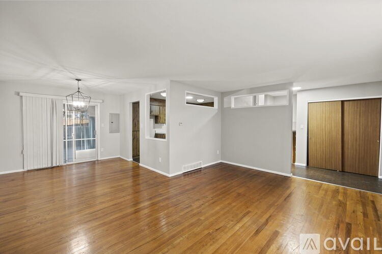 A spacious room with wooden flooring and white walls.