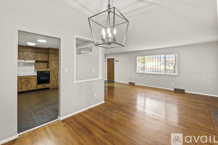 A spacious room with wooden floors and a large chandelier hanging from the ceiling.