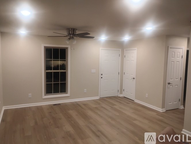 A room with a ceiling fan and wooden flooring.