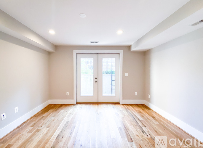 A spacious room with wooden floors and a large door leading to a balcony.