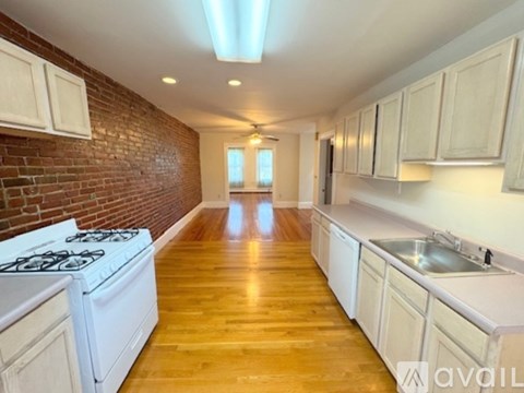 A kitchen with a white stove top oven and white cabinets.