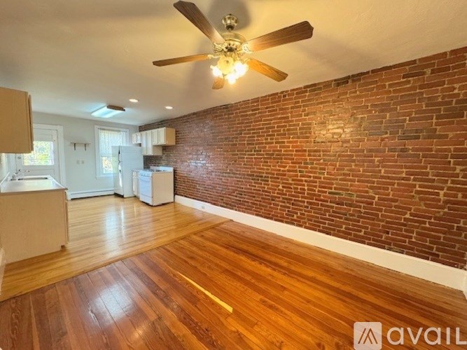 A room with a ceiling fan and wooden flooring.