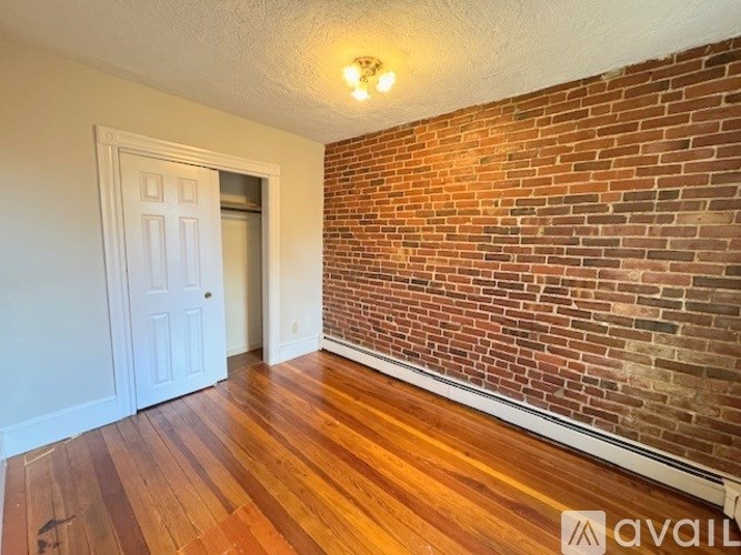A room with a wooden floor and a brick wall.