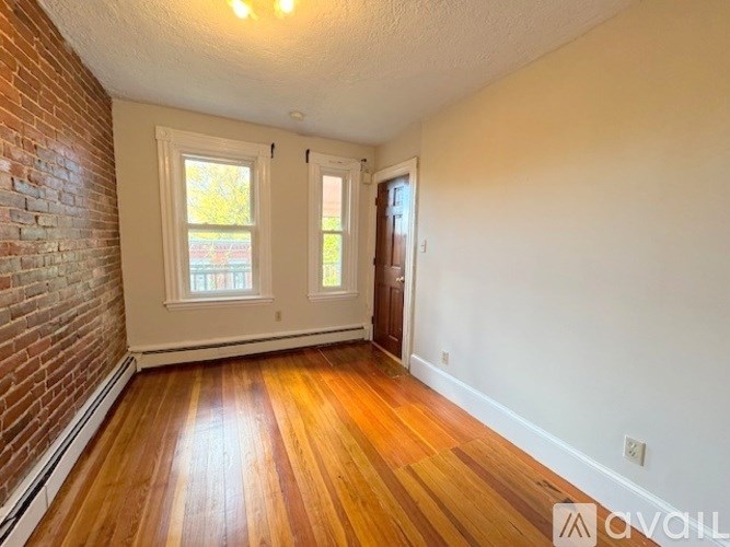 A room with wooden floors and a brick wall.