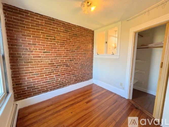 A room with a brick wall and wooden flooring.