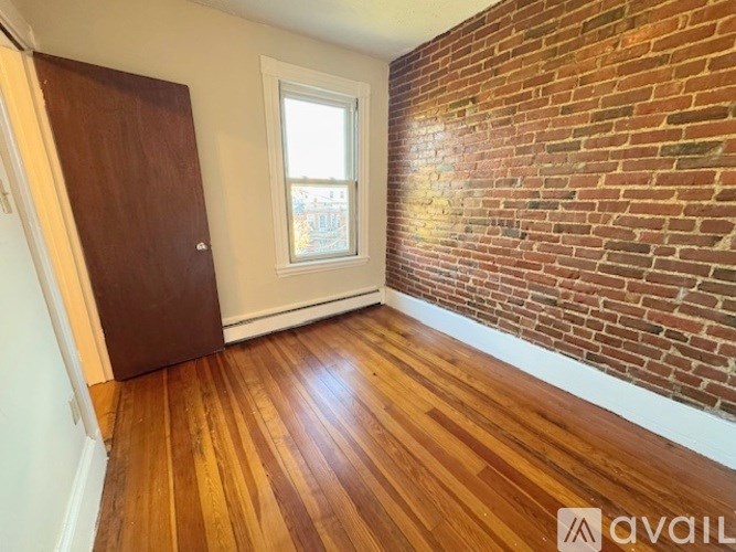 A room with a wooden floor and a brick wall.