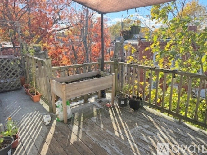 A wooden table is on a deck with a view of a tree with orange leaves.