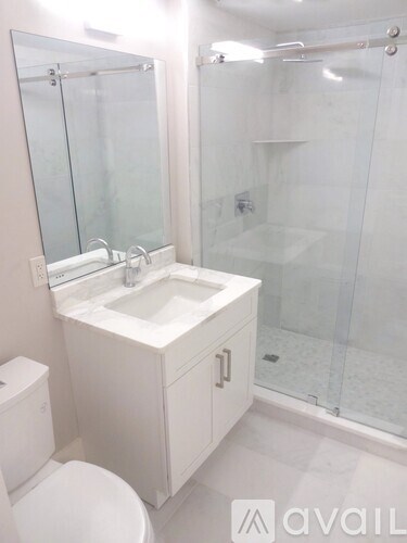 A white bathroom with a toilet, sink, and shower.