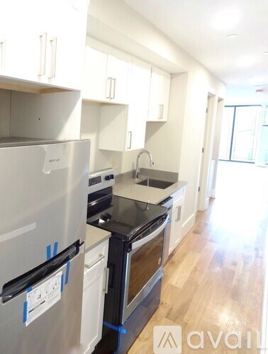 A kitchen with a refrigerator, oven, and sink.