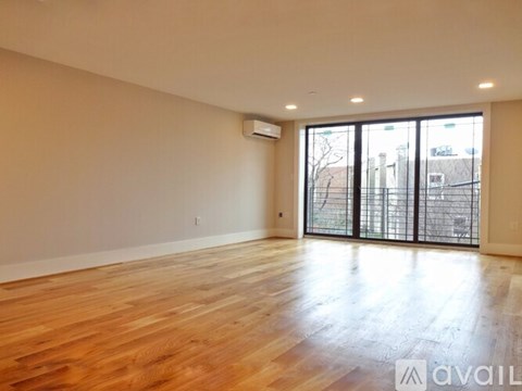 A spacious room with wooden flooring and sliding glass doors.