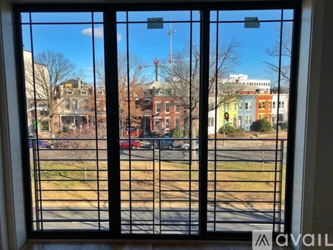 A view from a window looking out to a street with cars and buildings.