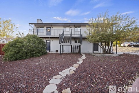 A house with a red brick driveway and a tree in front.