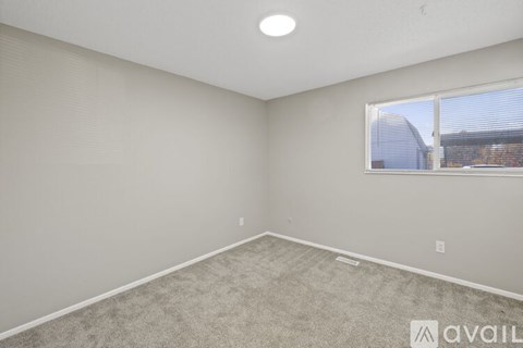 A room with a carpeted floor and a window showing a building outside.