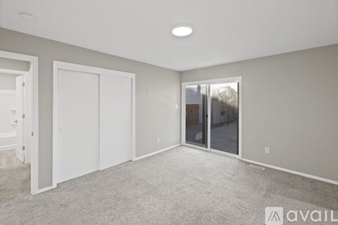 A spacious room with a carpeted floor and a sliding glass door leading outside.