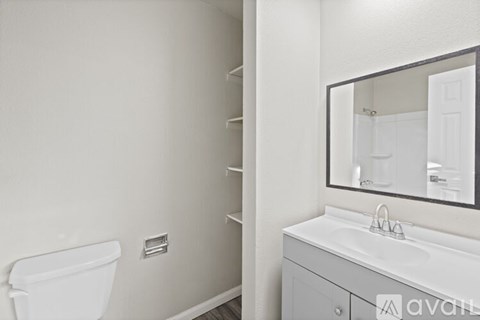 A white bathroom with a sink, mirror and toilet.