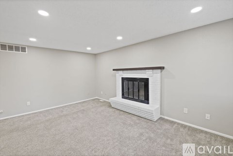 A spacious room with a fireplace and carpeted floor.