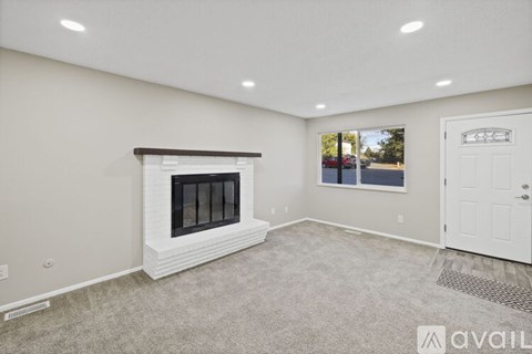 A spacious living room with a fireplace and a view of the street through the window.