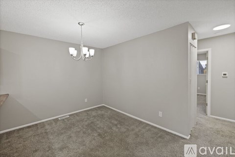 A room with a carpeted floor and a chandelier hanging from the ceiling.