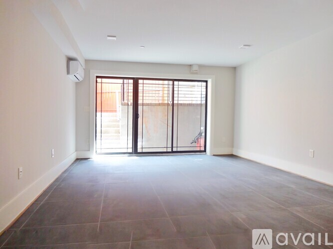 A spacious room with a sliding glass door leading to a balcony.