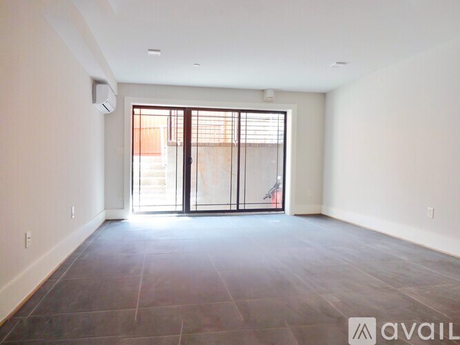 A spacious room with a sliding glass door leading to a balcony.