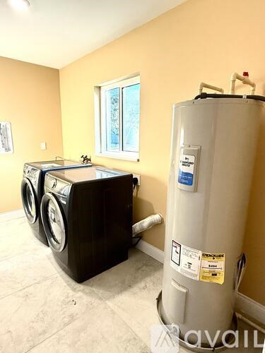 A room with a washer and dryer and a water heater.