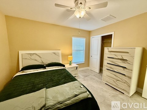 A bedroom with a bed, dresser, and ceiling fan.
