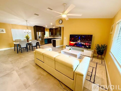 A living room with a white sofa and a television displaying a night scene.