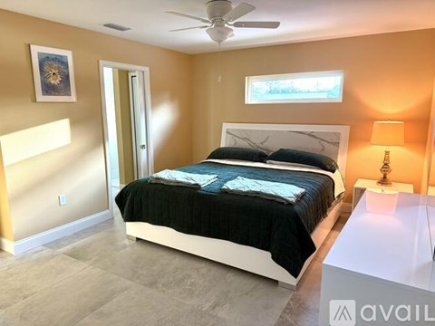A bedroom with a bed, a ceiling fan, and a lamp.