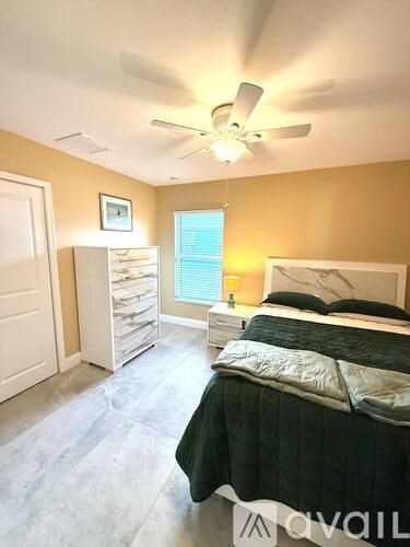 A bedroom with a bed, dresser, and ceiling fan.