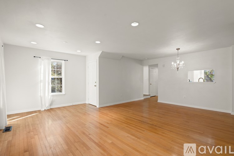 A spacious room with wooden floors and white walls.