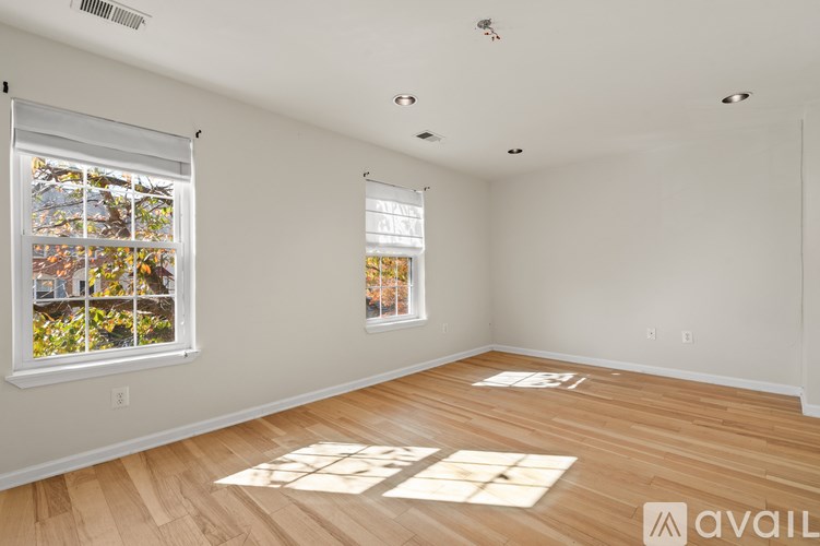 A room with wooden floors and two windows.