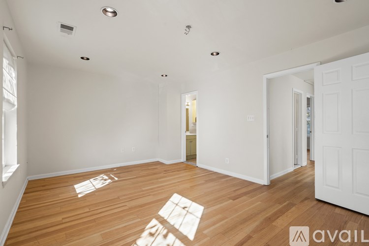 A room with wooden floors and white walls, with a doorway leading to another room.