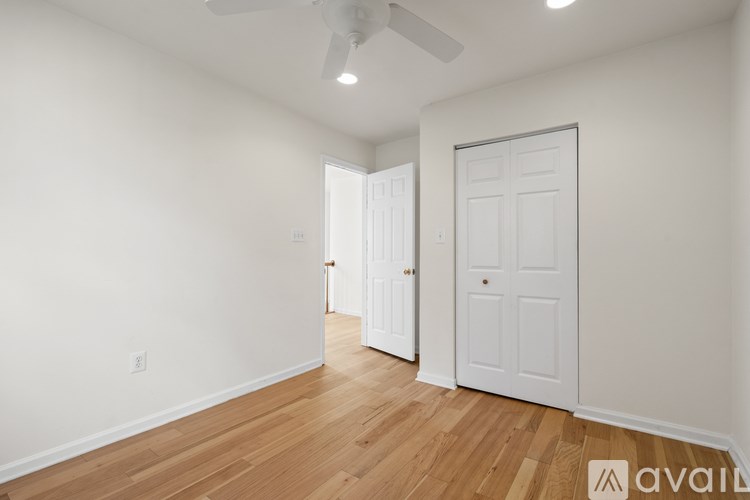A room with a white door and a ceiling fan.